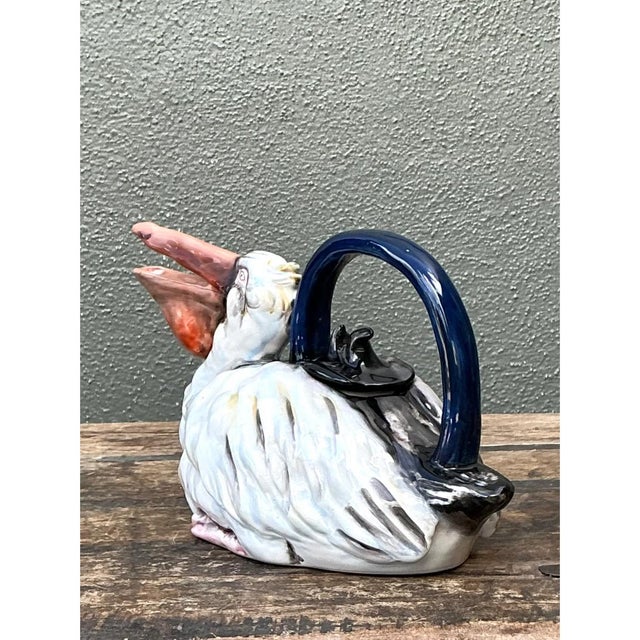 This vintage glazed ceramic teapot takes the whimsical form of a plump pelican nestled in repose, its rounded body...