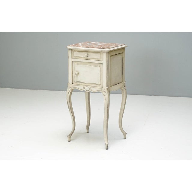 Bedside cupboard with rose marble top on cabriole legs (repainted). France Circa 1900 H 84cm x W 42cm x D 37cm This piece...