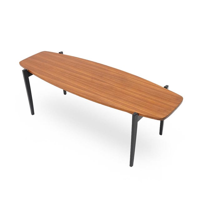 Italian-made coffee table from the 1960s. The veneered wooden top features a soft, lozenge-shaped form, reflecting the...