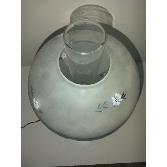 Vintage gone with the wind table lamp featuring frosted milk glass body and shade with blue floral design.