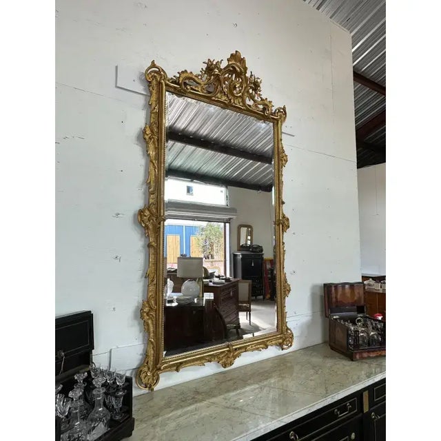Masterpiece 19th century French Louis XV carved and giltwood mirror. Featuring a floral design and a crest at the top....