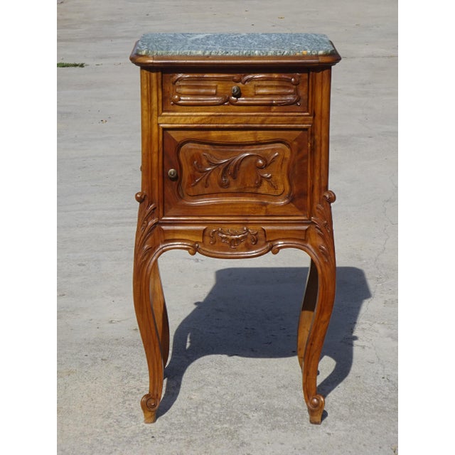 An elegant bedside table crafted entirely from solid walnut, featuring rounded curves and tall, cabriole legs in the louis...