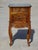 An elegant bedside table crafted entirely from solid walnut, featuring rounded curves and tall, cabriole legs in the louis...