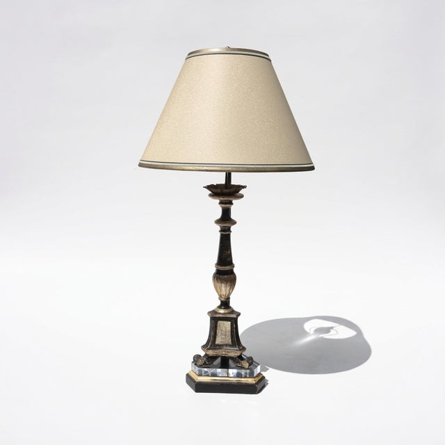 Pair of early 19th-century carved wood candlesticks, painted black and parcel-silver-gilt, adapted as table lamps. The...