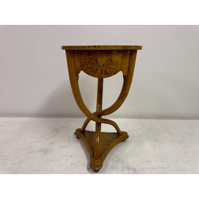 An elegant Italian burr wood occasional table, dating to the early 20th century, notable for its fluid lines and refined...