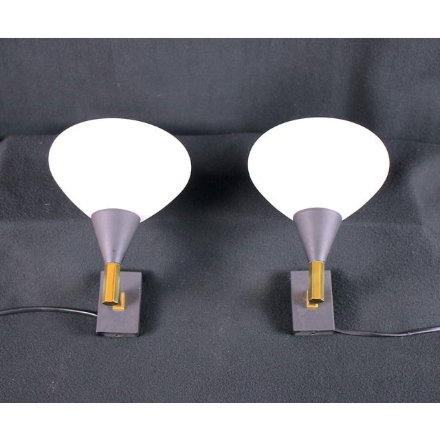 Superb pair of sconces attributed to "Stilnovo", with a white opaline saucer, black metal structure and brass rod, made in...