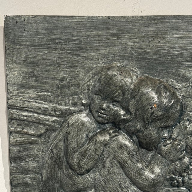 A striking vintage figural bas-relief wall plaque depicting two children gathered together among grapes, foliage, a...