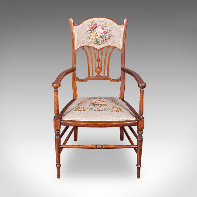 This is an antique elbow chair. An English, needlepoint over beech and mahogany morning room seat in Art Nouveau taste,...