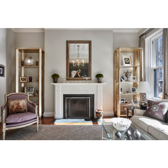A handsome pair of Brentwood bookcases purchased from the Nancy Corzine showroom finished in a rich gilt that catches the...
