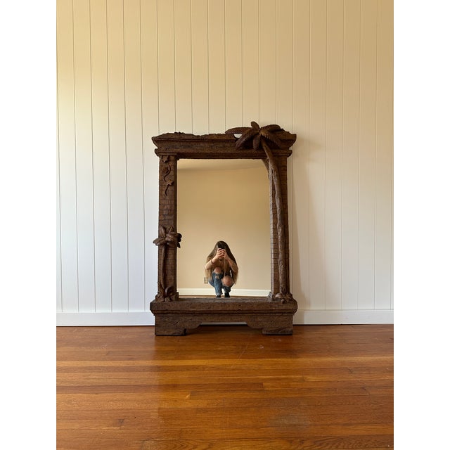This oversized coastal wall mirror features a sculptural palm tree motif that rises along the right side of the frame and...