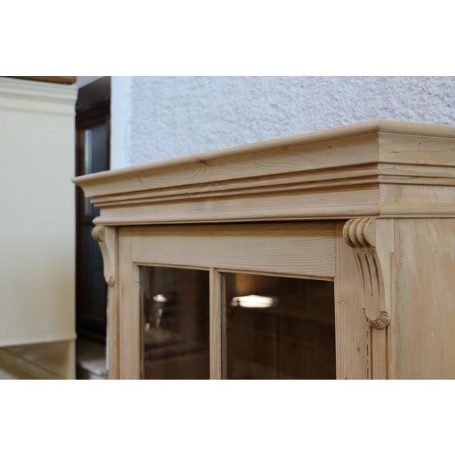 Antique display cabinet made of yellow-brown spruce wood. Handcrafted in farmhouse furniture style with three shelves. The...