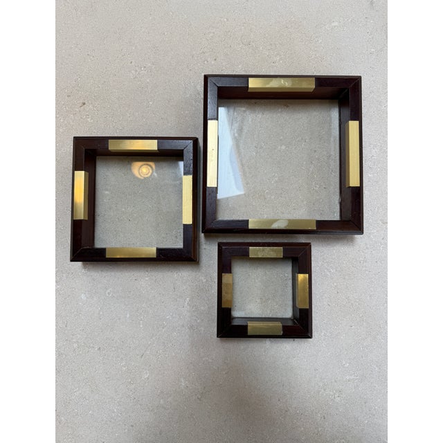 Set of three square Italian decorative trays crafted in dark stained wood with inset brass accents, arranged in a...