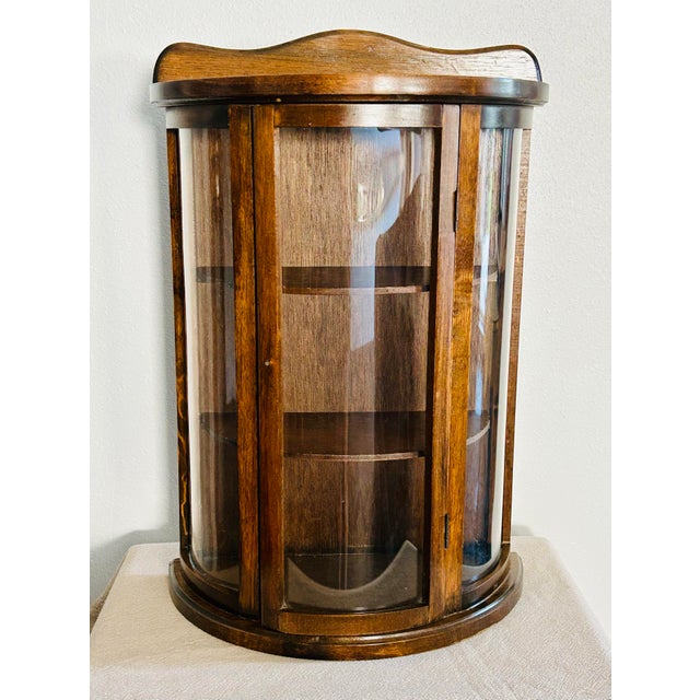 A great example of mid-century display cabinets. This gem features three, curved glass panels and wood shelves. Front...