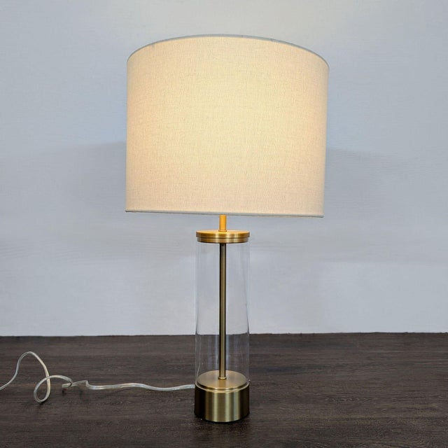 Brighten your space with this stylish West Elm table lamp. It features a clear acrylic cylinder base with brass accents...