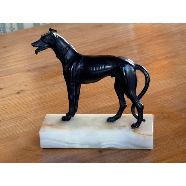 19th century dark patinated metal greyhound standing alert with mouth open and tongue showing, wearing a buckled collar,...