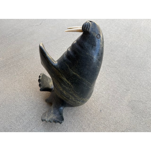 Gorgeous sculpture by Adamie. A well known Intuit artist. Fluid design with tawny streaks in the black polished stone.