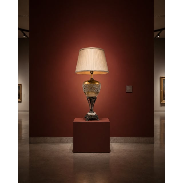 A vintage-style ornate table lamp featuring a warm gold-toned glass body, intricate decorative patterning, antique bronze-...
