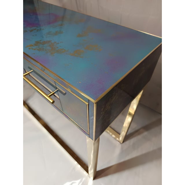 Discover our artistic glass console table with two drawers, featuring elegant blue glass accented with gold leaf and...