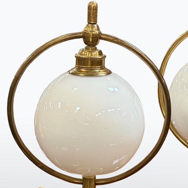 A pair of table lamps from the first half of the 20th century, crafted from solid brass and opaline glass. The spherical...