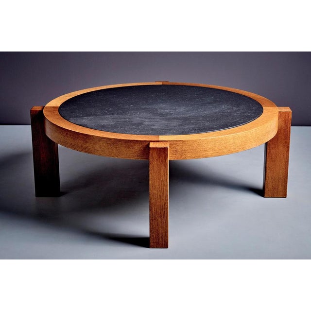 Round coffee table with dark slate stone top and oak frame. The stone has a natural textured surface, contrasting with the...