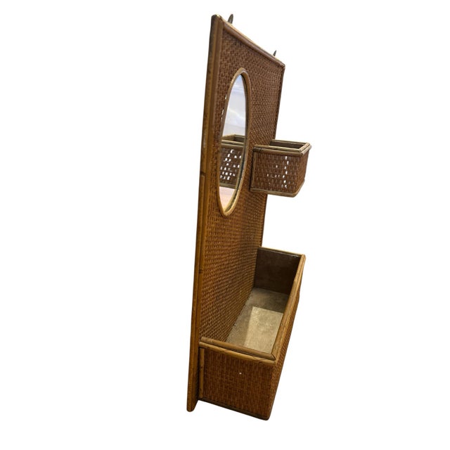 Fun wicker wall organizer with small oval mirror. It has one small compartment next to the mirror and a long compartment...