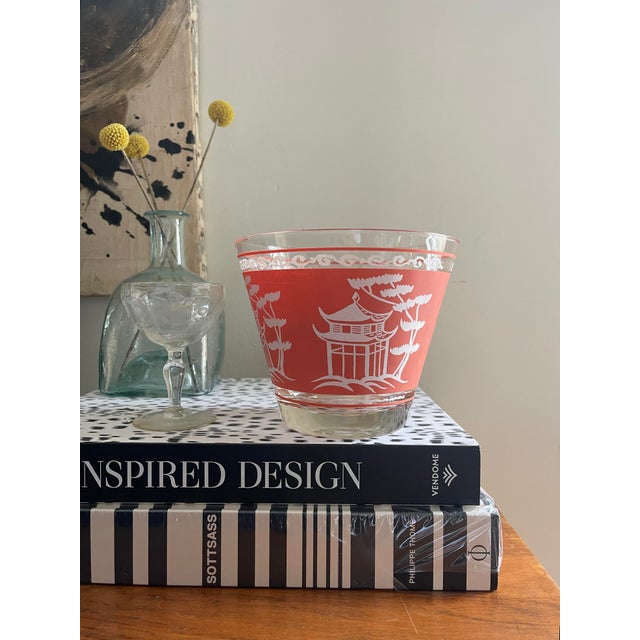 Fabulous glass ice bucket, made in the 1960s, a coral pink band through the center with a silhouette of pagodas and white,...