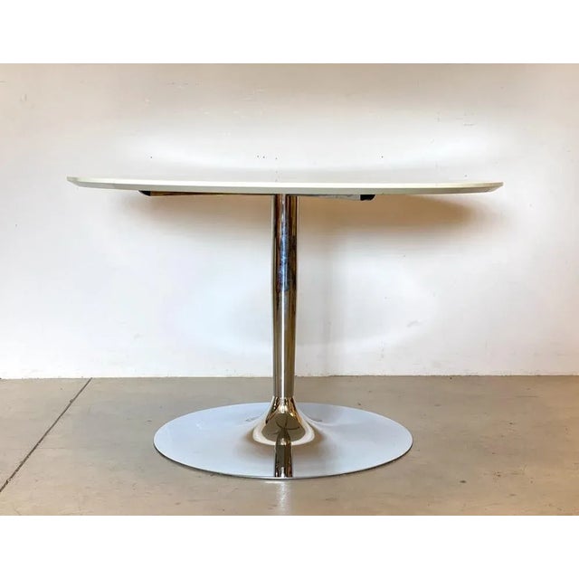 Round 1990s table produced by the Calligaris company, ivory lacquered wooden top and chromed steel base. This piece has an...