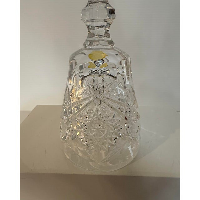 A striking vintage cut crystal bell showcasing a classic starburst and hobstar pattern, reminiscent of traditional cut...