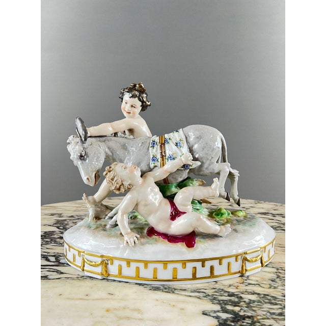 Large Capodimonte Porcelain Figurine Charming polychrome porcelain composition depicting two putti playing with a donkey....
