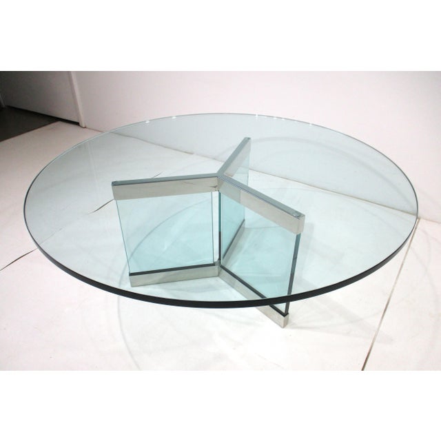 A glamorous round plateglass coffee table with three panel matching base having heavy chrome accent strips to the tops and...