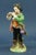 A polychrome hard-paste porcelain figurine depicting a pied piper boy, signed under the base with a crown over an "N" in...