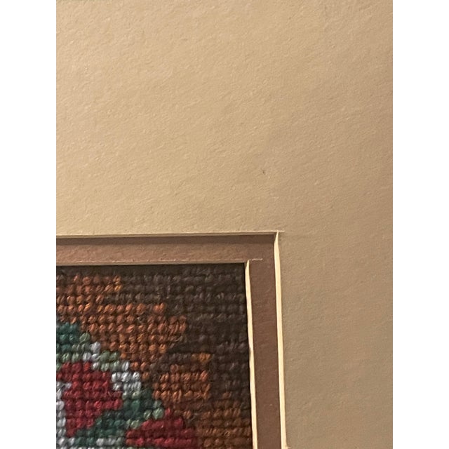 This is a vintage framed Southwestern or Native American-style longstitch/needlepoint art piece depicting a patterned...