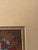 This is a vintage framed Southwestern or Native American-style longstitch/needlepoint art piece depicting a patterned...