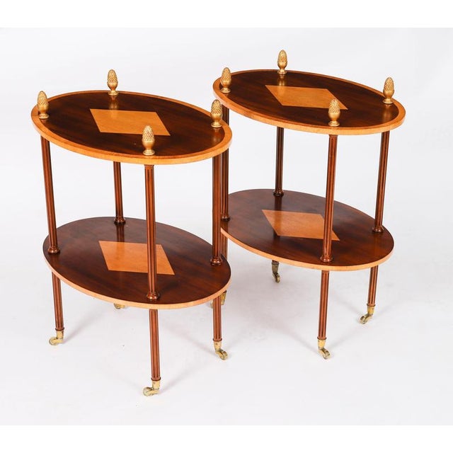 This is a wonderful vintage pair of flame mahogany and satin wood oval etagere tables, dating from the late 20th century....