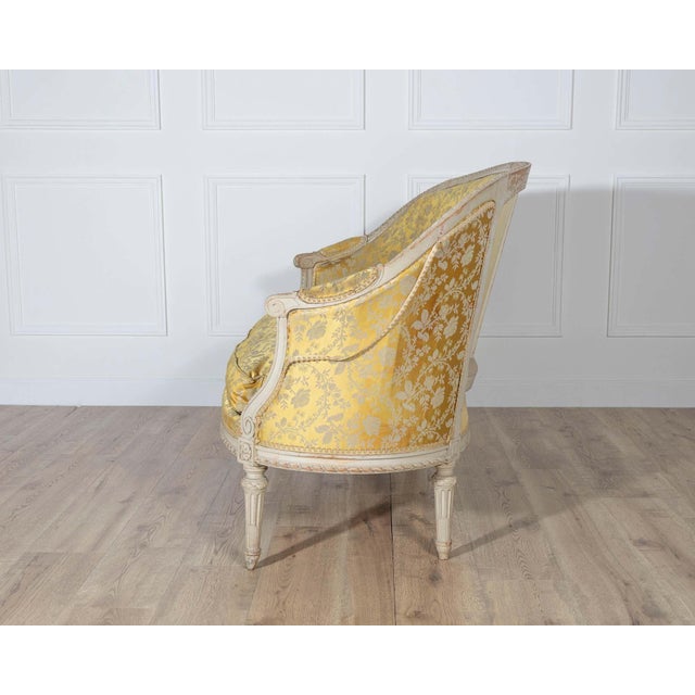A beautiful and refined French Louis XVI style canapé, 20th century, featuring an elegantly carved painted frame and...