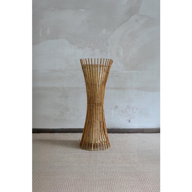 Crafted with bamboo canes in an hourglass structure. Internally, the fabric lining emits a diffused light. This piece is...