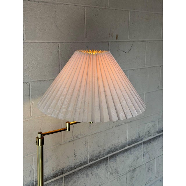 This elegant floor lamp features an adjustable swing arm and a classic pleated shade that casts a warm ambient glow....