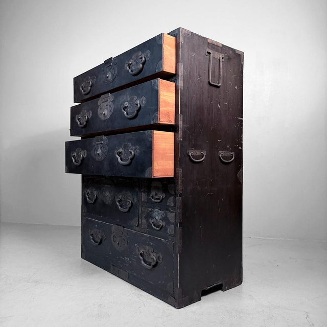 This large, dark-finished Japanese tansu from the Meiji period (around 1900) is a striking statement piece with a...