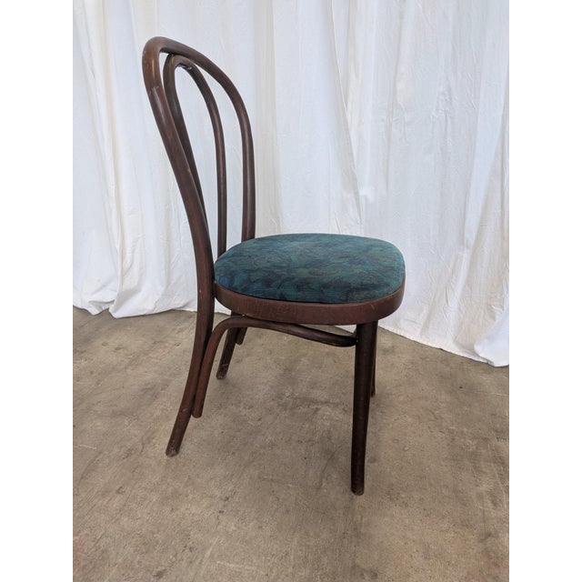 This vintage bentwood chair features a classic Thonet-style design with elegantly curved wooden elements and a rounded...