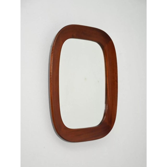 Elegant wall mirror with a curved frame in solid mahogany. The mirror features a rectangular shape with generously rounded...