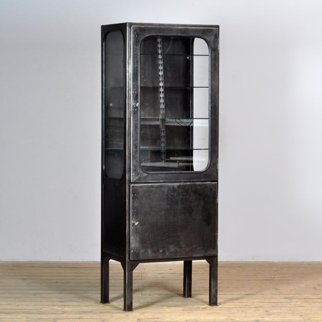 Vintage medicine cabinet from the 1970s, produced in Hungary. The cabinet is made of iron and glass, with the glass held...