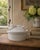 A charming vintage ceramic covered dish fashioned as a resting rabbit, its gently modeled head and long ears forming the...