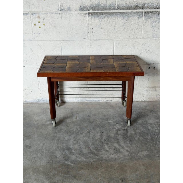 This mobile coffee table features an inset glazed ceramic tile top and a convenient lower wire rack. Smooth rolling...