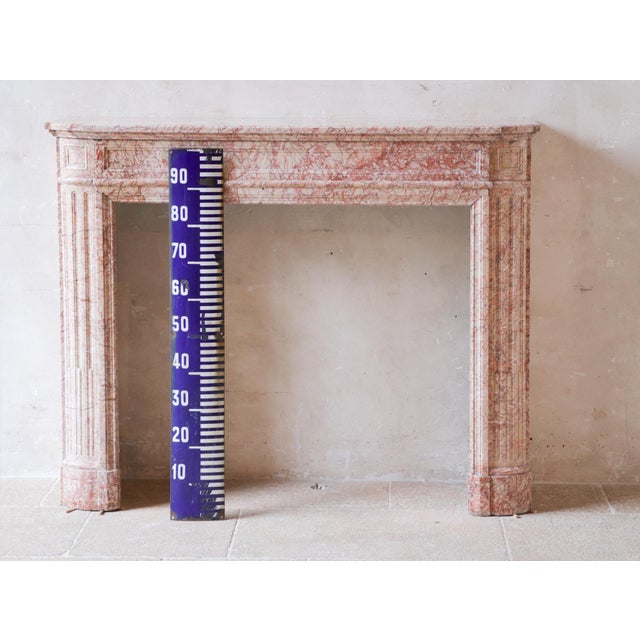Antique French marble fireplace in pink tones. A 19th century Demi Lune Louis XVI mantelpiece in Trets marble, with fluted...