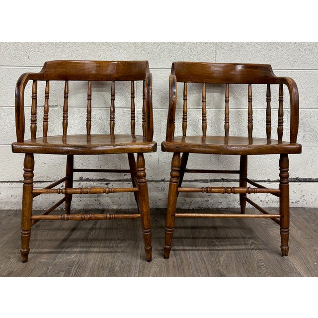 This is a gorgeous fantastic pair of antique primitive 19th-century oak barrel-back pub or captain’s armchairs featuring...