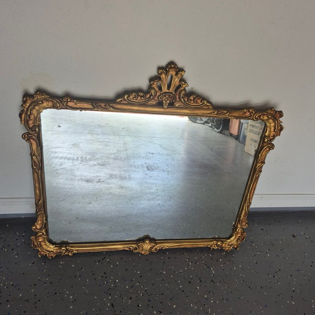A Regency style gilt wall mirror. The rose gilt frame has a Rococo shell decoration all the way around the rectangular...