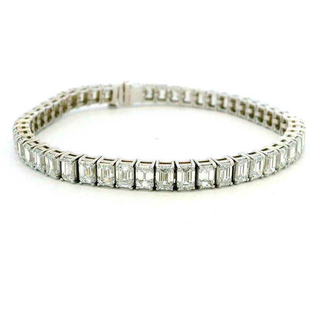 Crafted in 18 karat white gold, this elegant tennis bracelet is set with 51 beautifully matched emerald-cut natural...