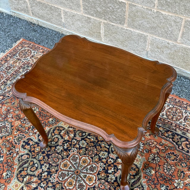 A vintage Knob Creek Traditional Queen Anne solid cherry side table having a scalloped and beveled top over carved...