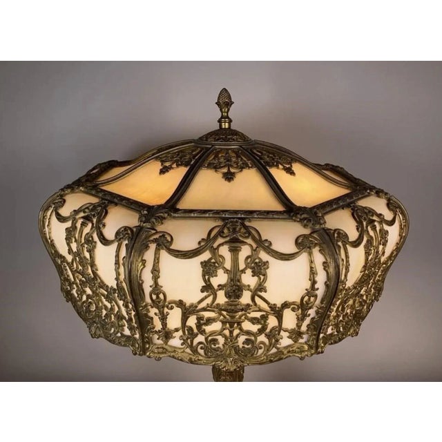 A large gilt bronze and bent glass table lamp, 24 inch diameter shade with original matching base. The glass is a pearly...