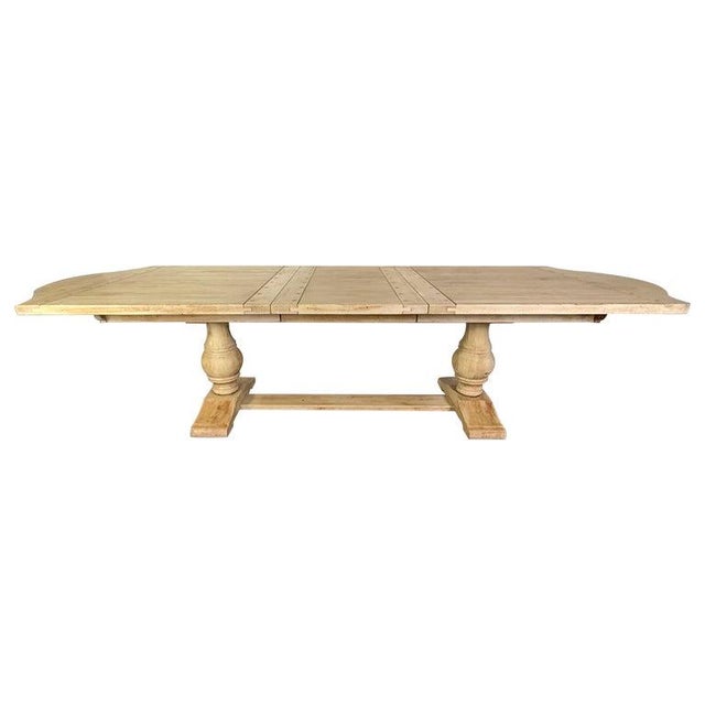 1930's Spanish rustic farmhouse style dining table with a distressed, light wood finish. It features a trestle base with...